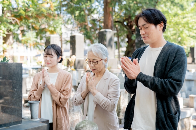 親子でお墓参りする（合掌）